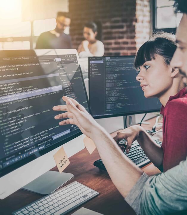 Zwei Entwickler, die sich Code am Bildschirm anschauen um eine Webseite für einen Online Shop zu entwickeln