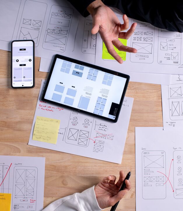 Unterlagen auf dem Schreibtisch, die das Design einer Webseite und Online Shops zeigen um eine gute Benutzererfahrung zu erreichen.